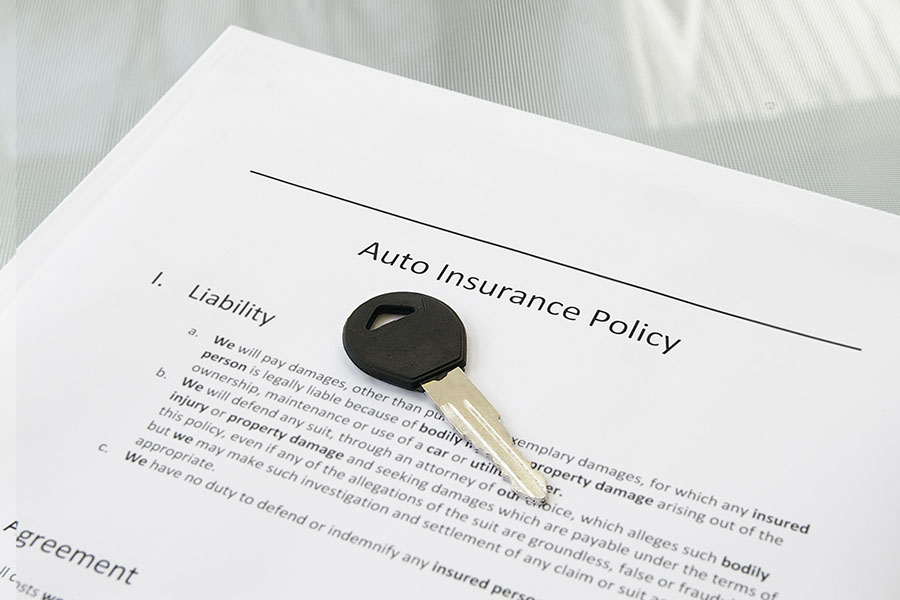 Closeup of a car key and auto insurance policy