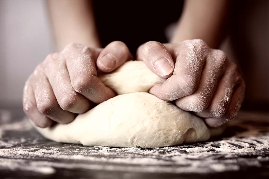Image of hands kneading pizza dough.
