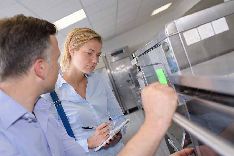Image of Woman inspecting kitchen, making notes