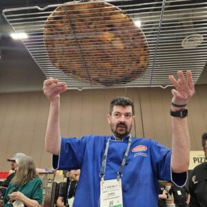 Chris Ostapenko of Slice on Broadway in Pittsburgh checks the bottom bake of his cheese pizza in the World’s Best Cheese Slice Championship at International Pizza Challenge at Pizza Expo in Las Vegas.