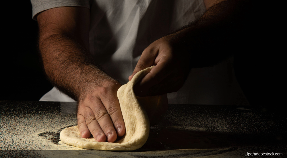 Image of kitchen staff stretching pizza dough.